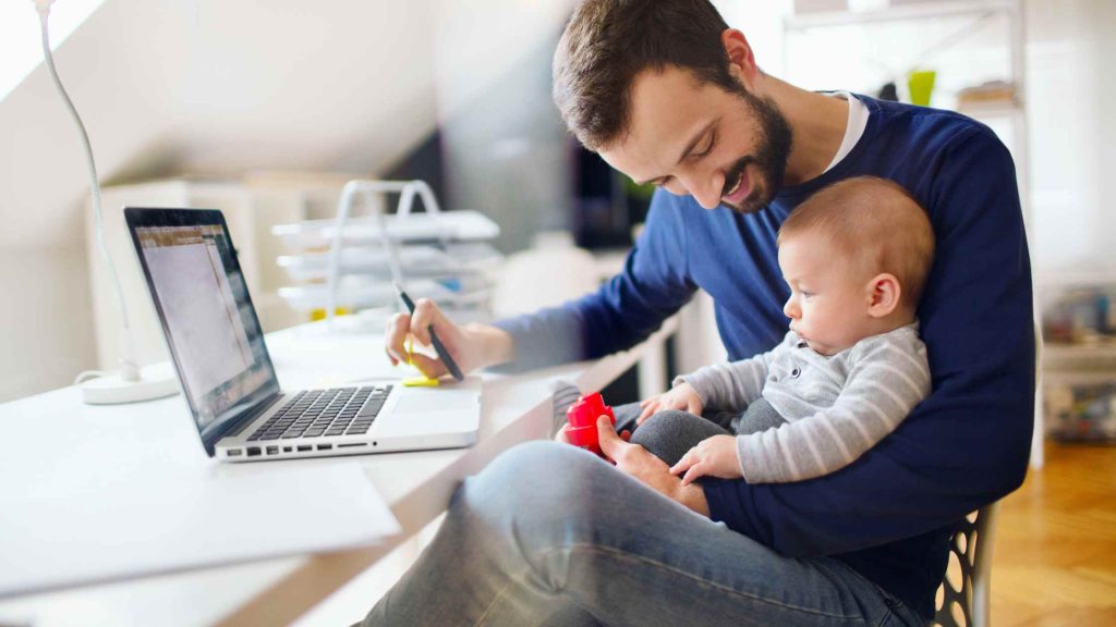 father holding his baby working from home